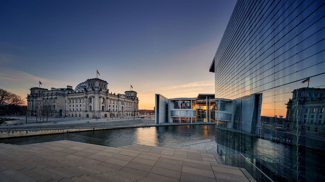 Der Berliner Reichstag am Spree-Ufer im Sonnenuntergang. 